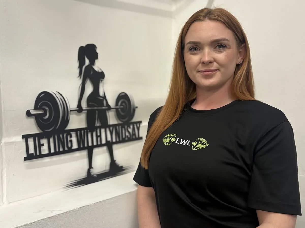 Lyndsay in her gym with the Lifting with Lyndsay sign