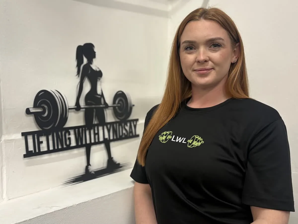 Lyndsay in her gym with the Lifting with Lyndsay sign